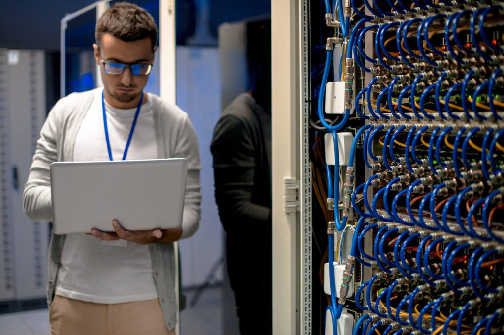 An IT professional managing and monitoring a server rack in a data center, ensuring optimized network performance through advanced cable connections and system diagnostics.